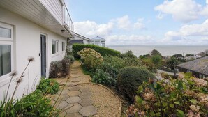 Una proprietà costiera con un vialetto in pietra che conduce a una casa con vista sul mare.