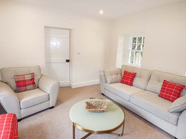 A living room with two sofas, a coffee table, and a door. - Beaver Grove Cottage (Betws-Y-Coed)