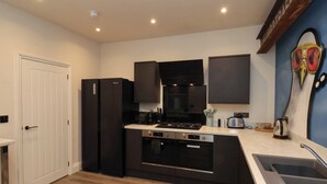 A modern kitchen with black appliances, a built-in oven, and a stainless steel sink. - 23 Trafalgar Square (Scarborough)
