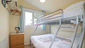 A bunk bed room with a wooden dresser and a window with curtains. - High Cove (Wadebridge)