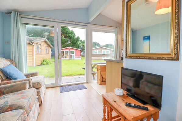 A living room with a sofa, a television on a wooden table, and a sliding glass door leading to a patio.