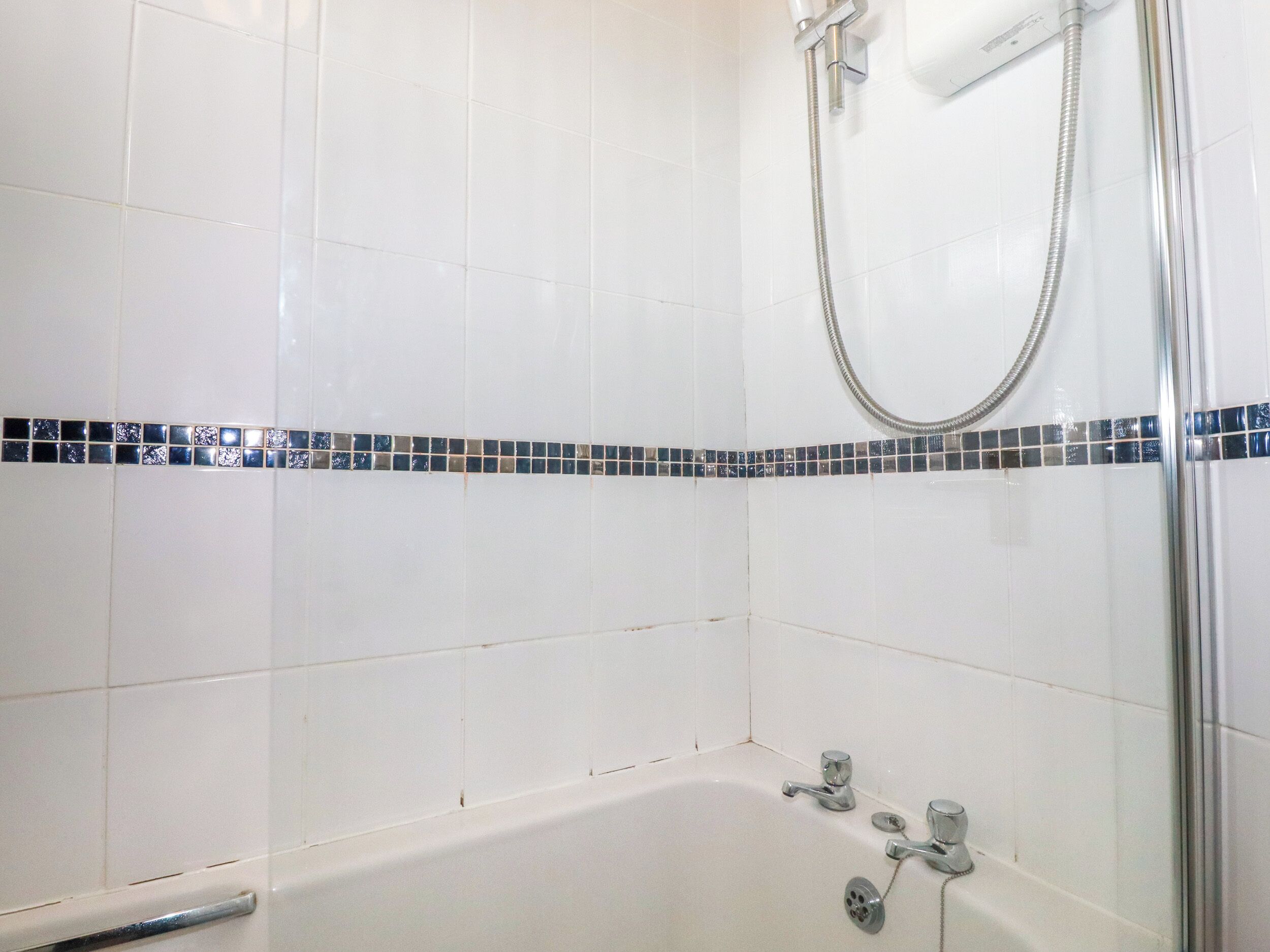 Un bagno con piastrelle bianche, una doccia e una vasca da bagno.