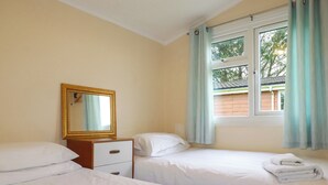 Une chambre d’hôtel avec deux lits, une commode, un miroir et une fenêtre avec des rideaux.