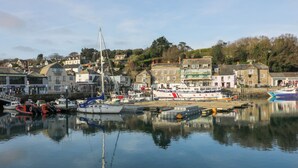 Un port avec des bateaux, un voilier et des bâtiments en arrière-plan.
