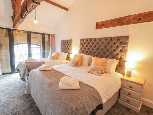 Une chambre spacieuse avec un grand lit, une tête de lit en bois et une table de chevet dotée de tiroirs.