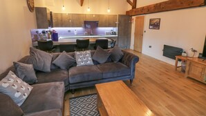 A modern living room with a grey sofa, a wooden coffee table, and a kitchen in the background. - Flying Scotsman @ Engine Shed (Whitby)