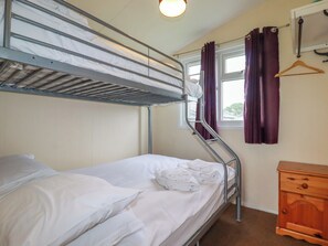 A bunk bed room with a window, a wooden dresser, and a hanging coat rack. - Pepper Cove (Wadebridge)