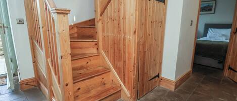 A wooden staircase leading to a bedroom with a bed and a nightstand.