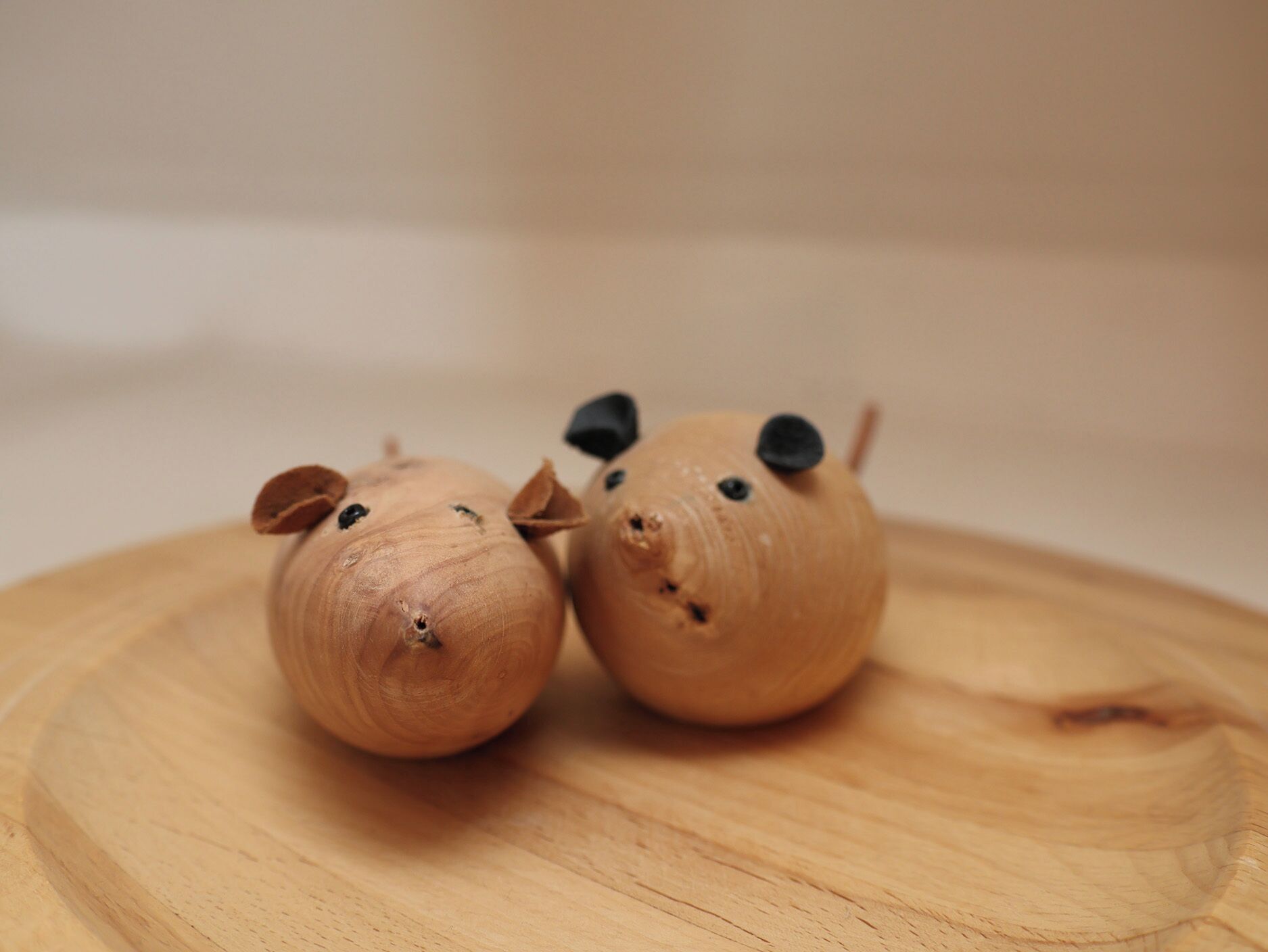 Two wooden pig figurines on a wooden surface.
