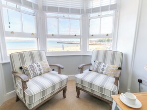 Una habitación con dos sillones a rayas orientados hacia un ventanal con vistas a la playa.