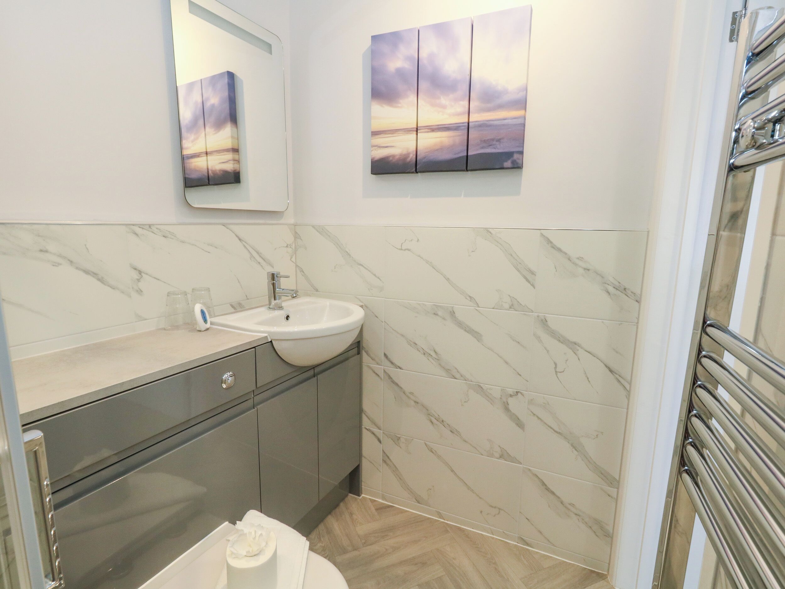 A modern bathroom with a marble backsplash, a sink, and a mirror.
