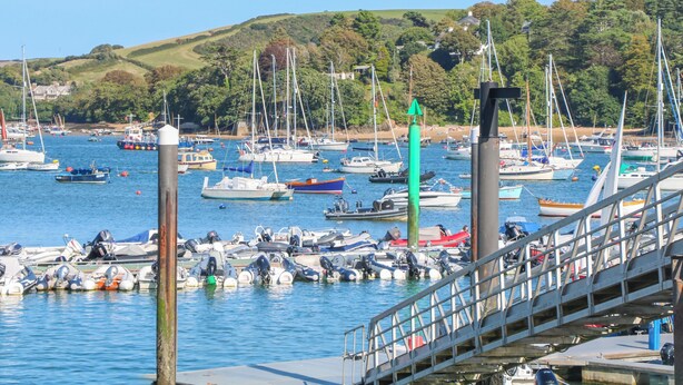 A marina with various boats docked, a bridge, and a hilly landscape in the background. - Old Police House (Salcombe)