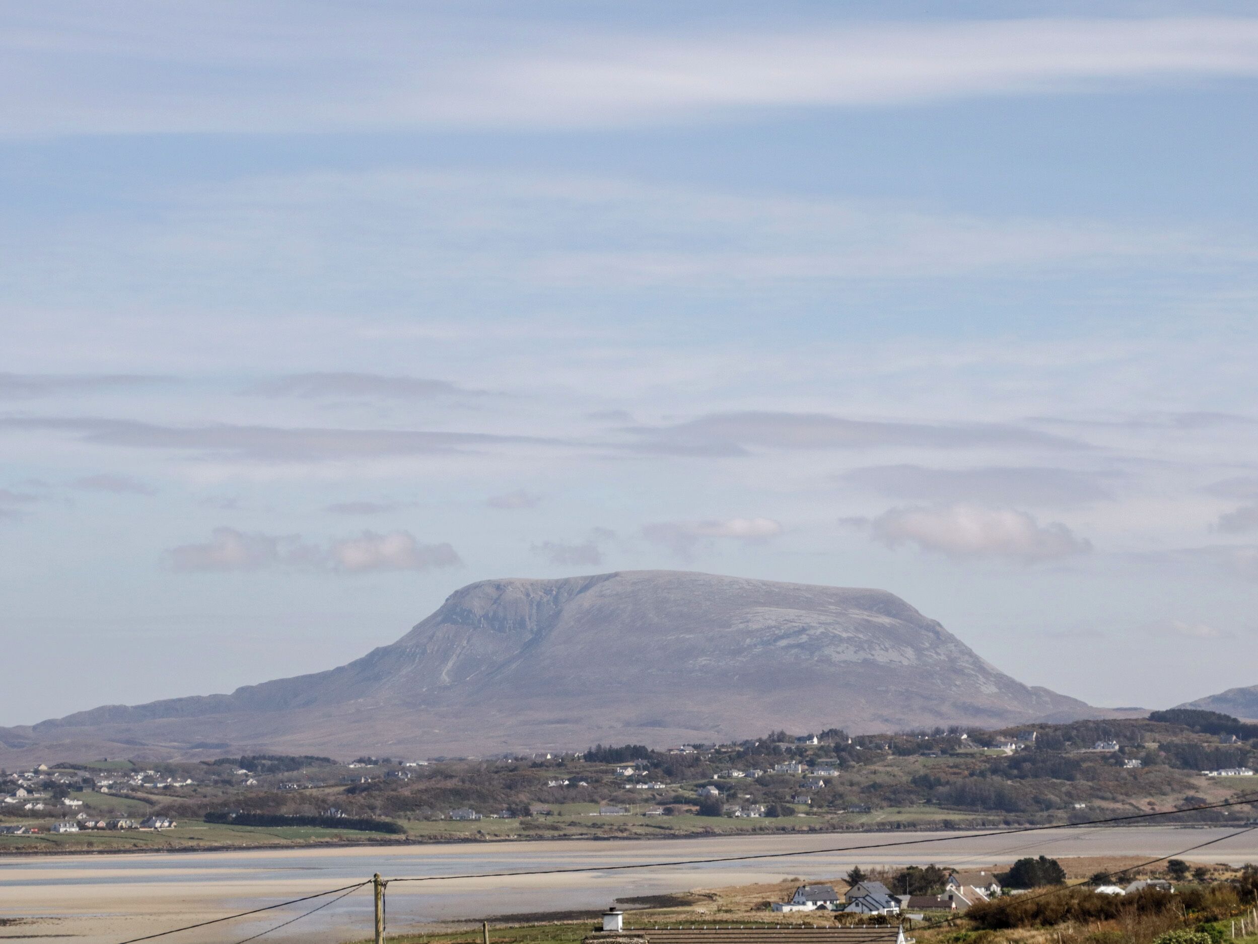 A mountain with a flat top, surrounded by a rural landscape with houses and fields.