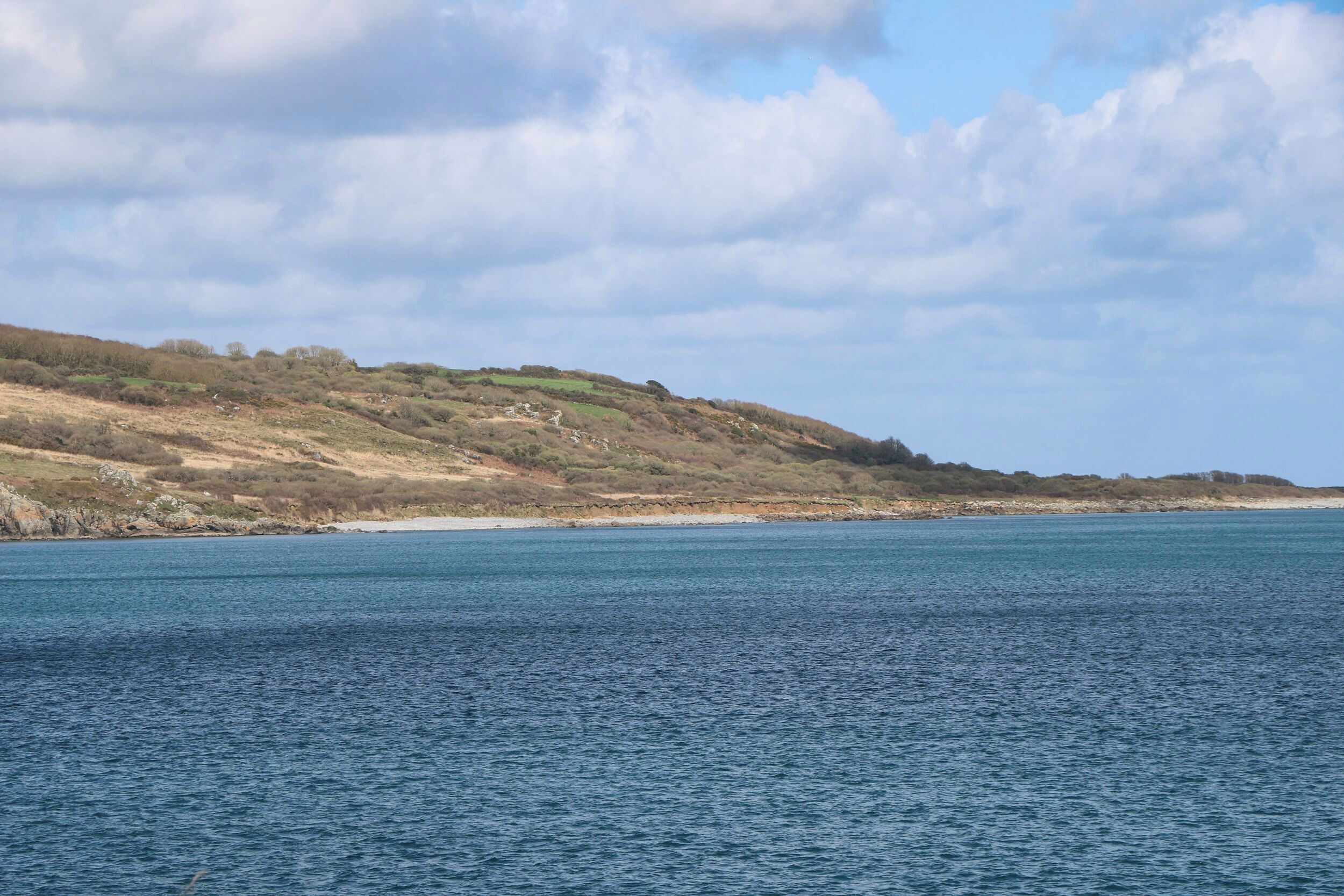 A coastal landscape with a beach and hills.