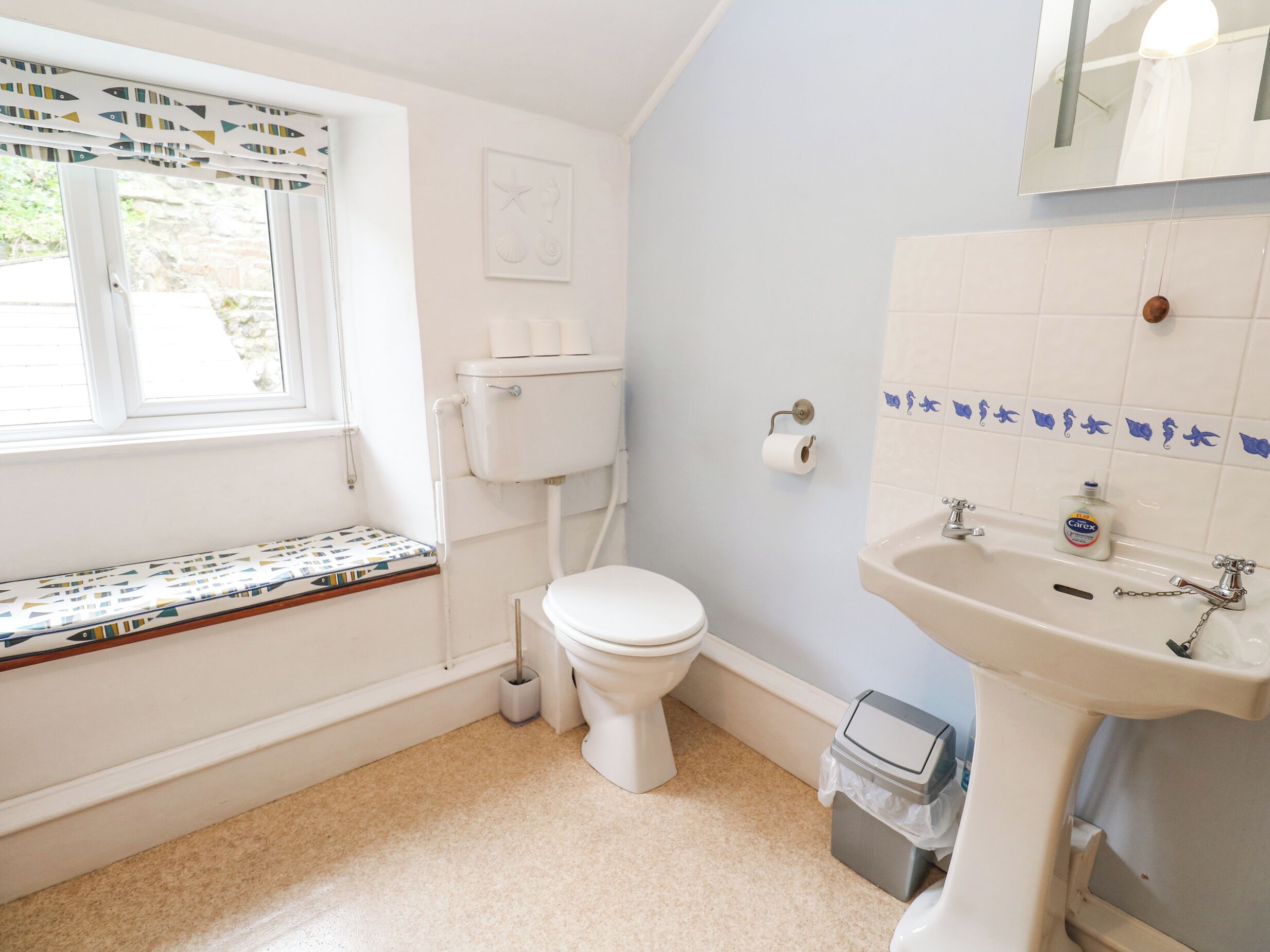 Un baño con inodoro, lavabo y ventana.