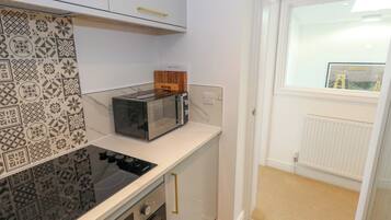 A compact kitchen with a modern toaster, a built-in oven, and a patterned backsplash.