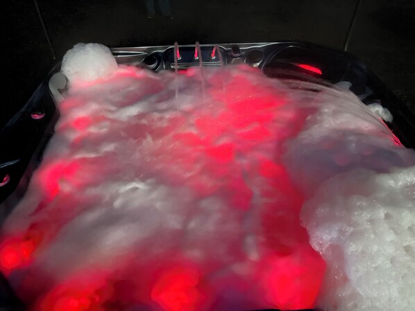 Eine mit Wasser und Schaum gefüllte Badewanne, beleuchtet mit rotem Licht.