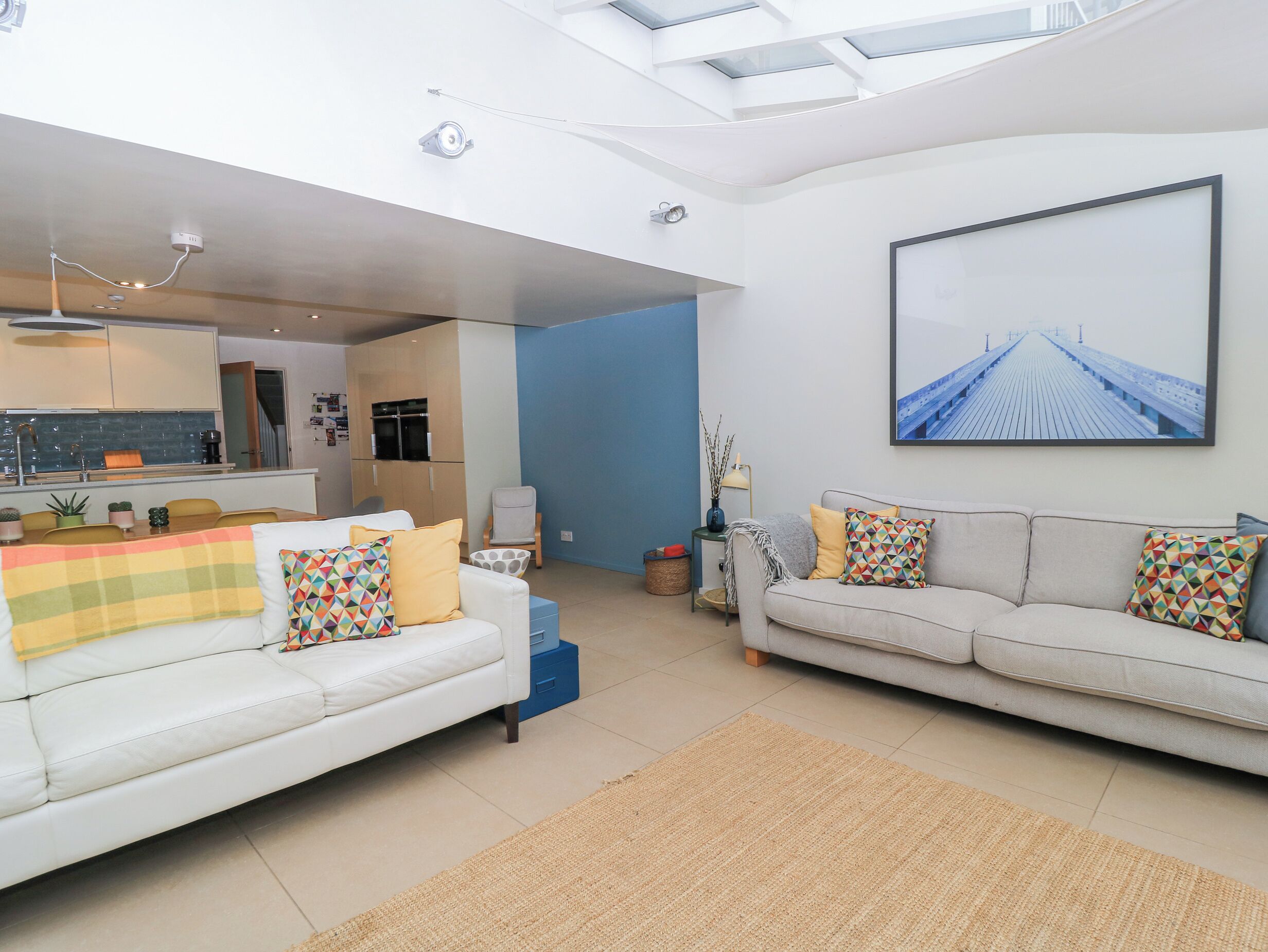 A modern living room with a sofa, a dining table, and a kitchen area.