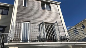 A two-story building with a balcony featuring a metal railing and a chair. - 6 Inveravon (Christchurch)