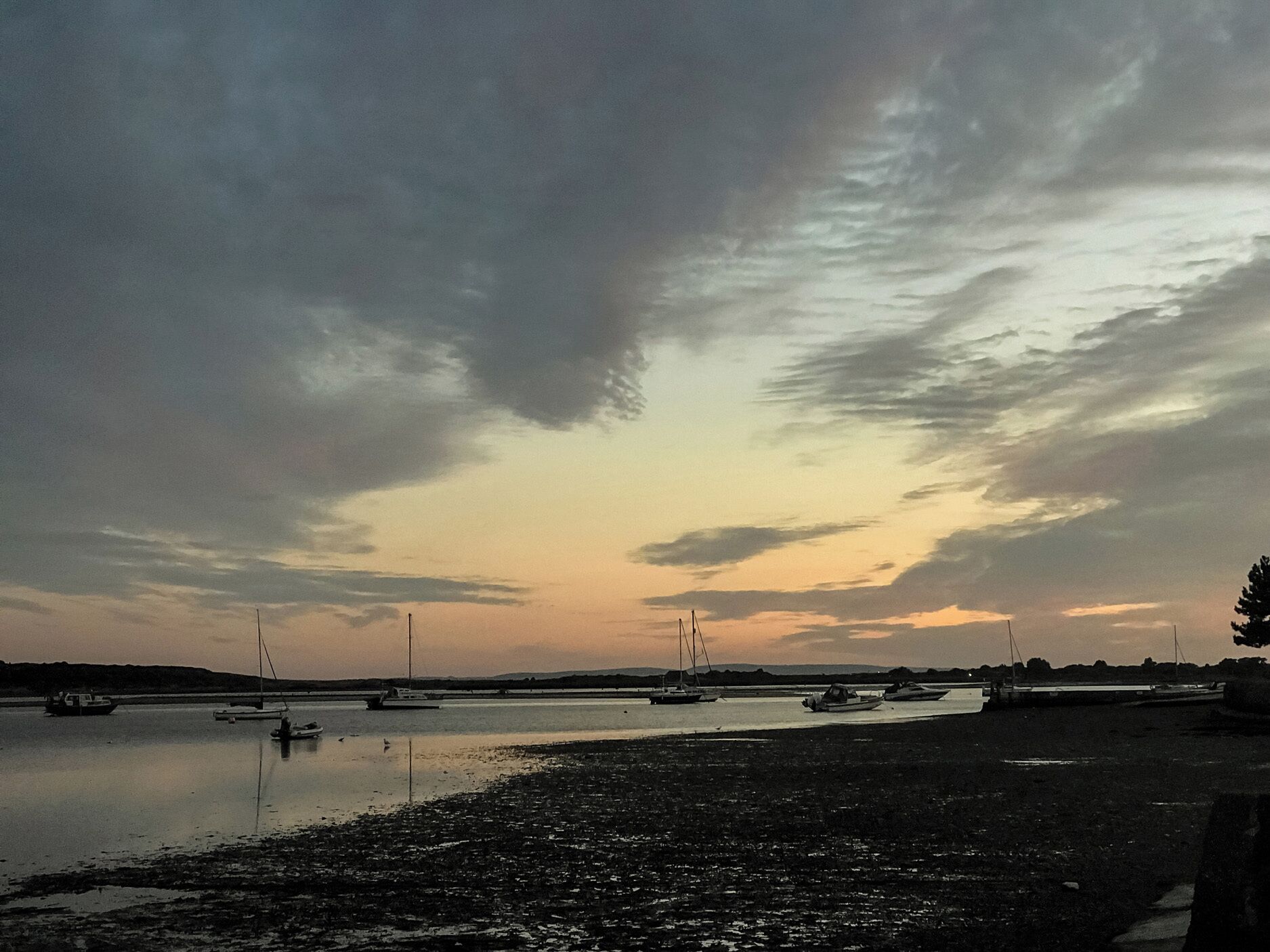 A calm waterfront with several boats anchored in the water.