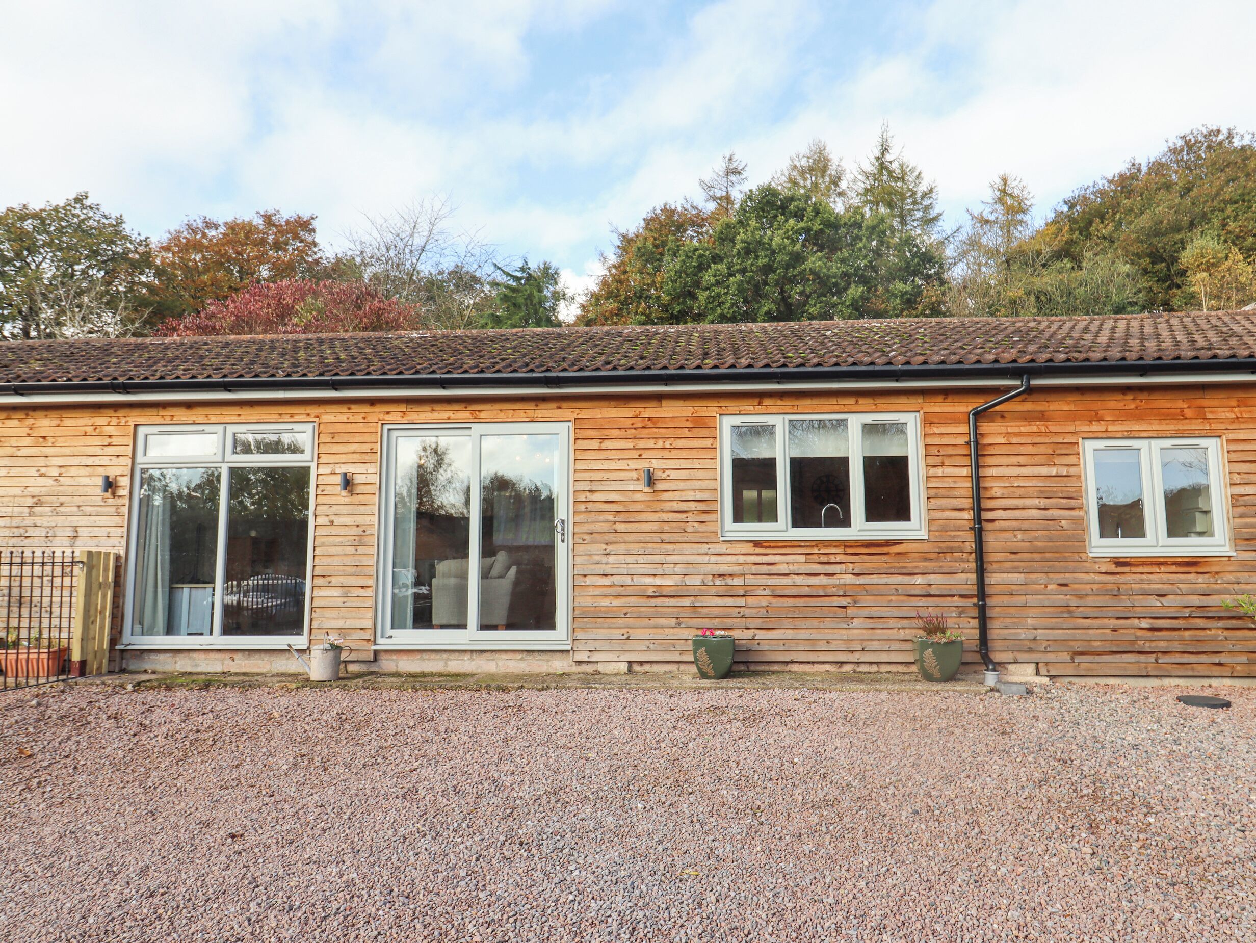 A wooden house with a gravel driveway and a tiled roof.