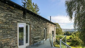 Un bâtiment en pierre doté d’un balcon, d’un banc et offrant une vue sur la campagne.