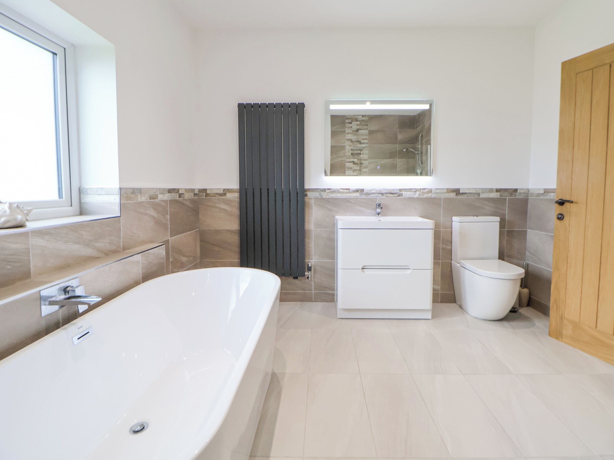 Ein modernes Badezimmer mit freistehender Badewanne, Toilette und Waschbecken.