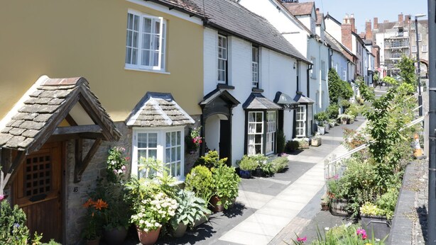 A narrow street lined with traditional houses, each with distinct architectural features like pitched roofs and white facades. - Troutbeck Cottage (Ludlow)