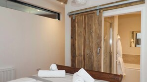 A bedroom with a large bed, wooden wardrobe, and a bathroom visible through an open door. - Brock House (Northallerton)