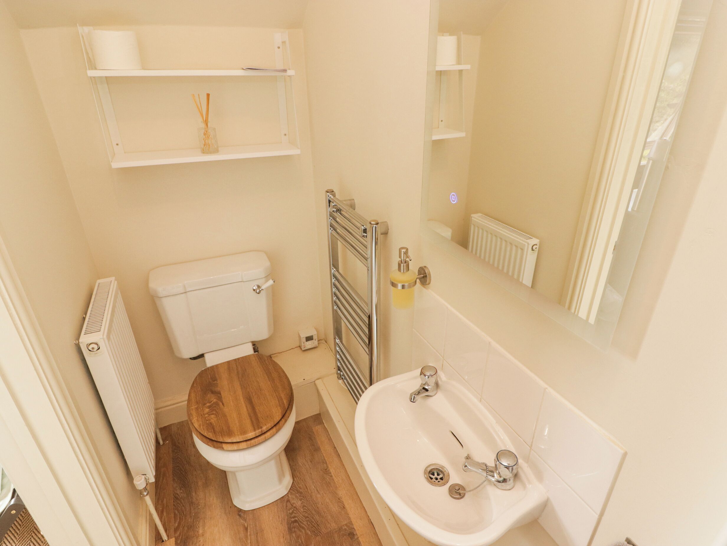 A small bathroom with a toilet, a sink, a mirror, and a radiator.