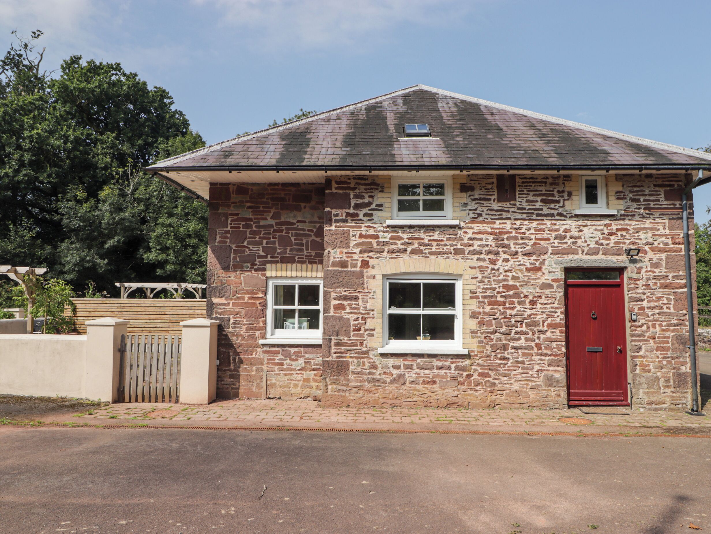 A stone building with a red door, two windows, and a small dormer window.