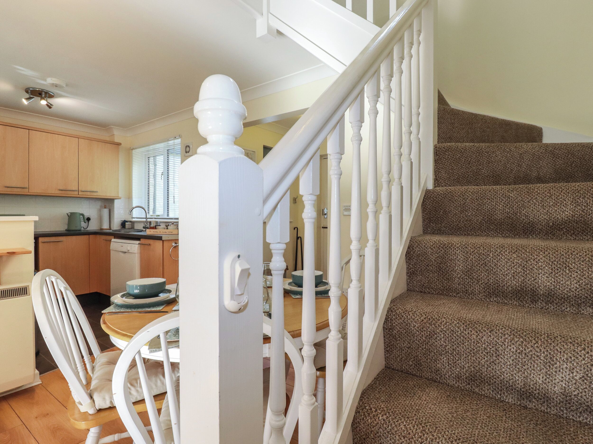 A staircase with white balusters leading to a carpeted landing.