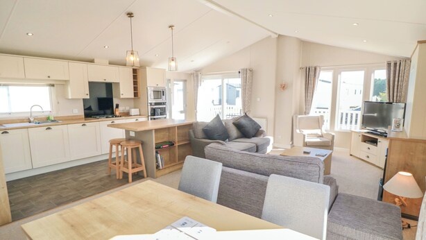 Eine moderne Wohnung mit Küche, Essbereich und Wohnzimmer. Sie verfügt über ein großes Fenster, einen Flachbildfernseher und ein Sofa.