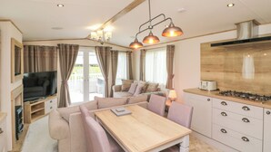 A compact living space with a sofa, dining table, kitchen area, and a TV. - Drake 11 (Scarborough)
