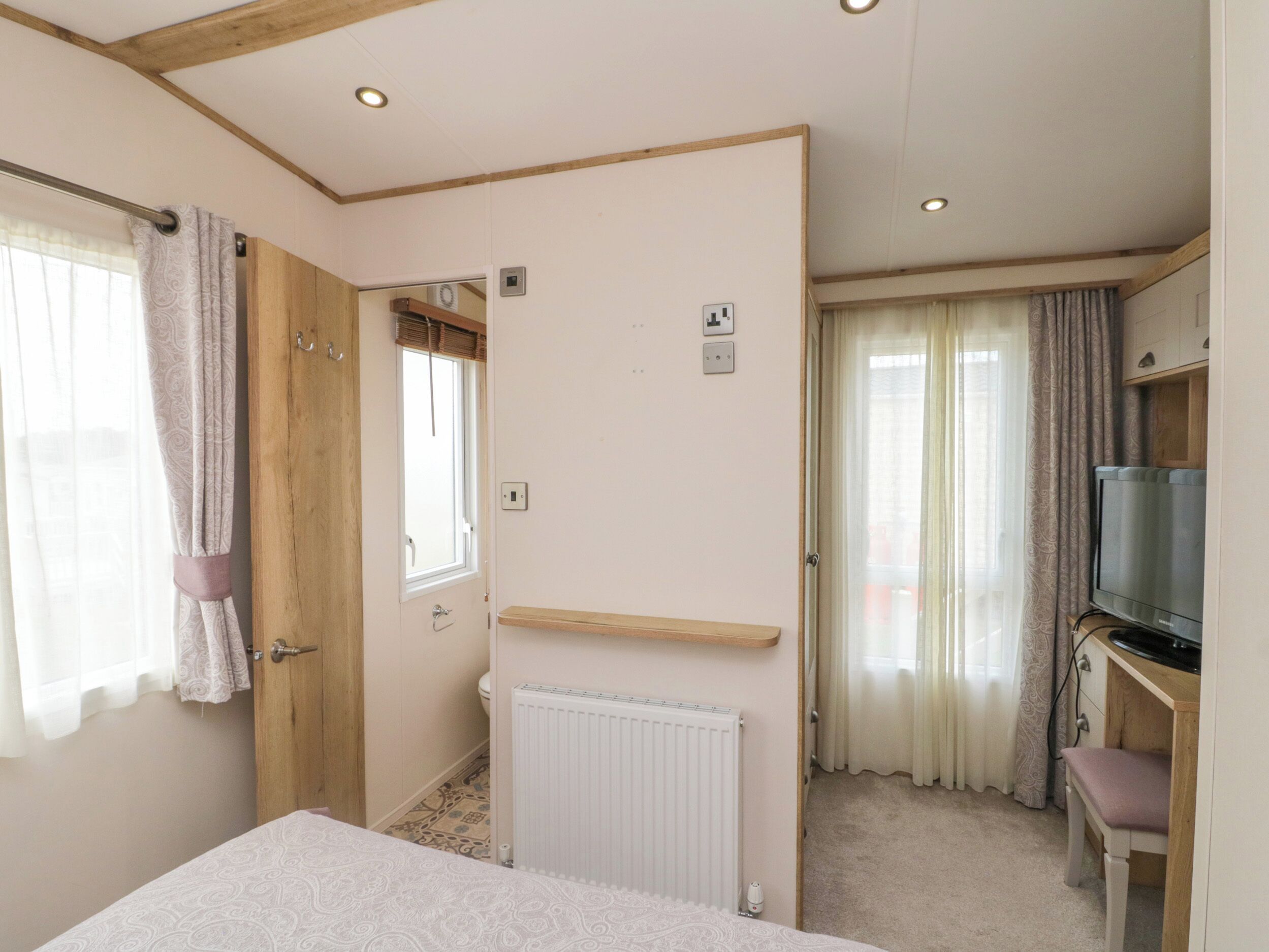 Une chambre à coucher avec un lit, un radiateur, une télévision et un bureau avec une chaise.