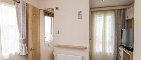A bedroom with a bed, a radiator, a TV, and a desk with a chair.