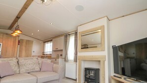 A cozy living room with a sofa, ottoman, fireplace, television, and wooden cabinets. - Drake 11 (Scarborough)