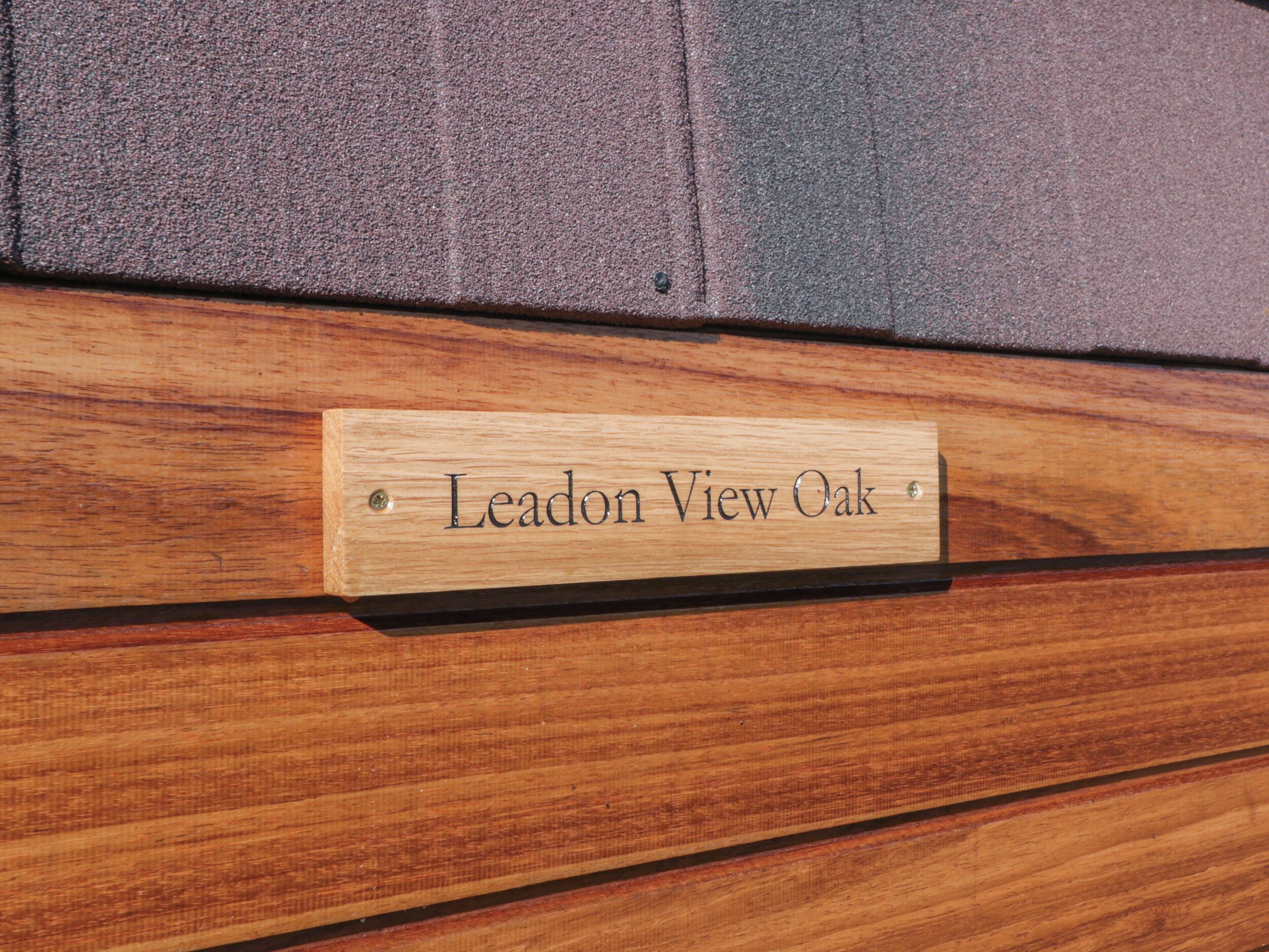 Una placa de madera con la inscripción 'Leadon View Oak' sobre una superficie de madera.