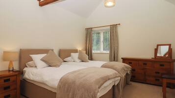 A bedroom with a large bed, wooden nightstands, a dresser, and a window with curtains.