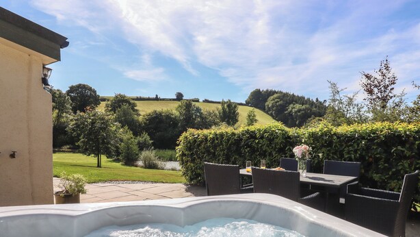 A hot tub in a garden with a view of a hill and trees. - Binneford Barn (Crediton)