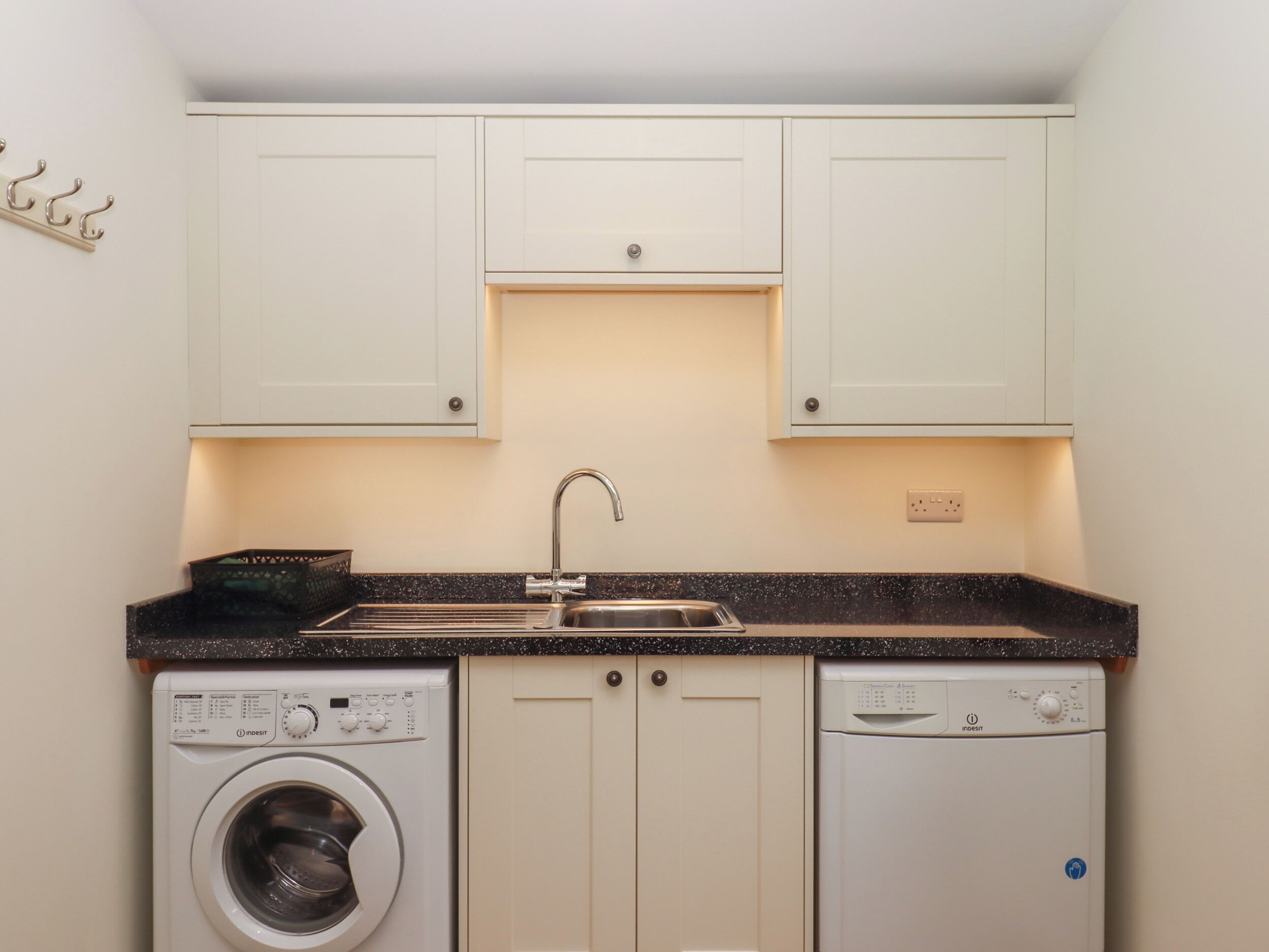 A compact kitchen with a washing machine, dishwasher, and a sink.
