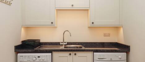 A compact kitchen with a washing machine, dishwasher, and a sink.