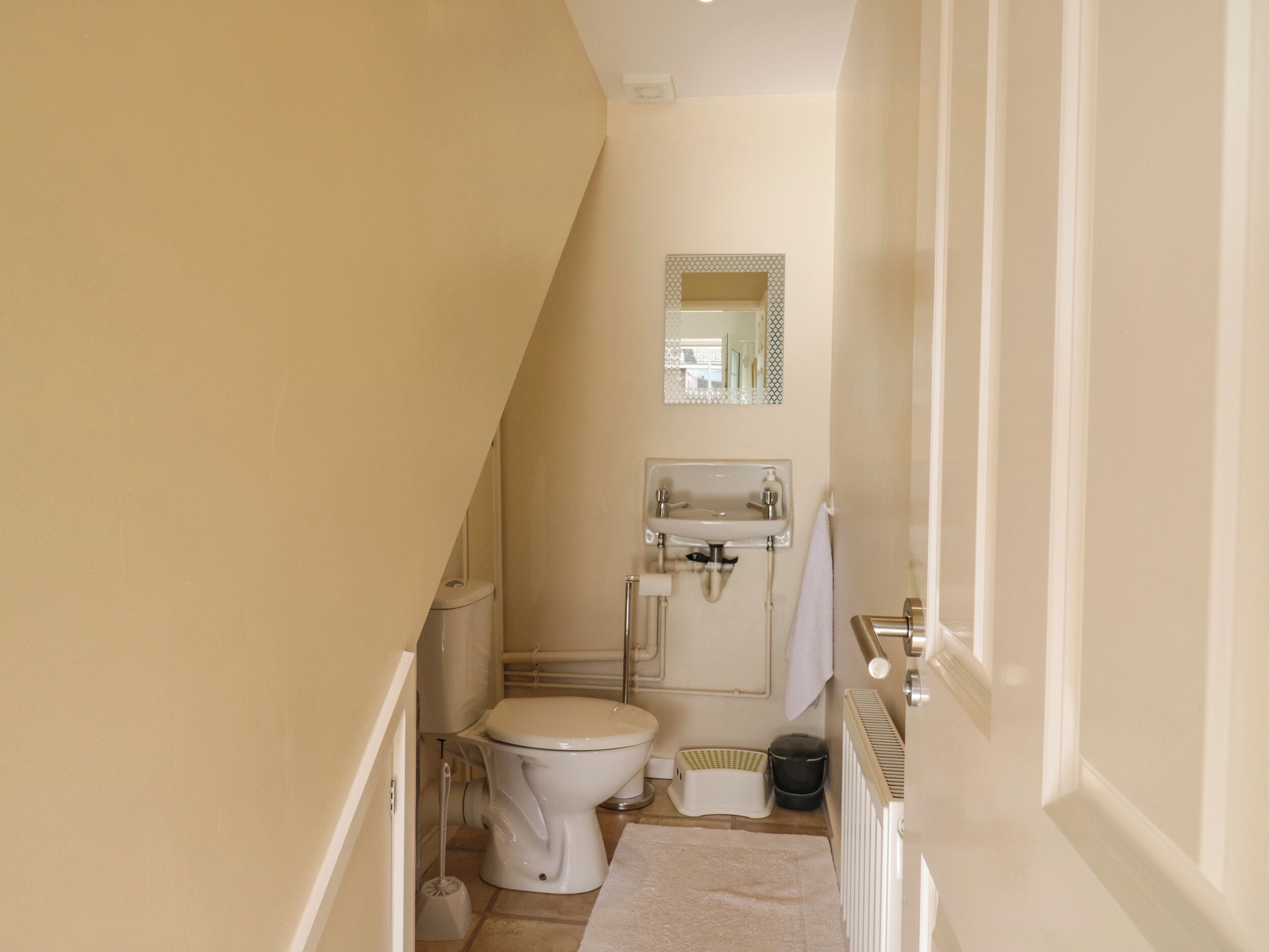 Ein schmales Badezimmer mit Toilette, Waschbecken und Spiegel.