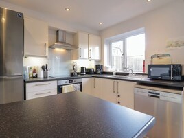 Una cocina moderna con electrodomésticos de acero inoxidable, lavavajillas y un ventanal que aporta luz natural.