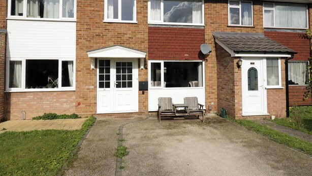 A two-story residential building with a front garden, a patio with two chairs, and a satellite dish. - 25 Resbury Close (Cambridge)