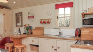 A kitchen with wooden cabinets, a bar area, and a window with a red valance.