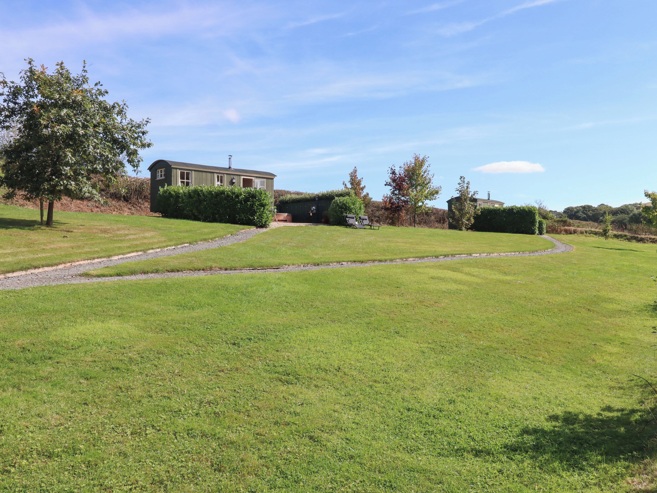 A grassy area with a building, a pathway, and trees.