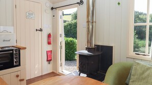 Une pièce chaleureuse avec un poêle à bois, une couverture anti-feu, un extincteur et un panneau indiquant l’emplacement des toilettes.