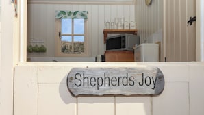 Une cuisine avec une fenêtre, une enseigne en bois sur laquelle on peut lire « Shepherds Joy », et des meubles de cuisine.