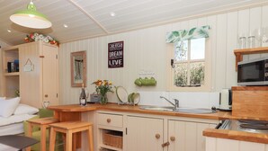 Une cuisine compacte avec des meubles en bois, un évier, un four à micro-ondes et un coin repas équipé de tabourets.